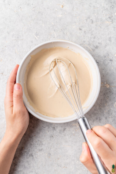 overhead image of bowl of tahini dressing with whisk