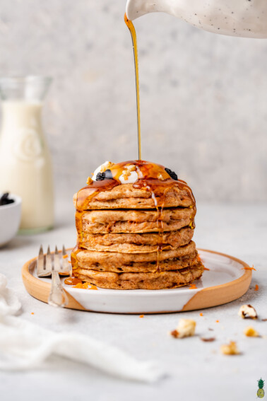 a stack of vegan carrot cake pancakes with a maple syrup drizzle