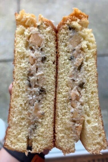 Mediterranean-inspired chickpea salad sandwich cut in half being held in hands