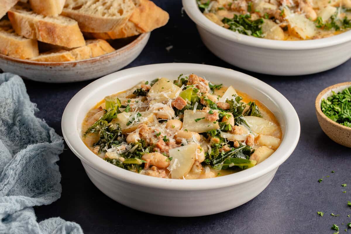 styled soup bowl with parsley and a napkin, bread and another bowl of soup in the background